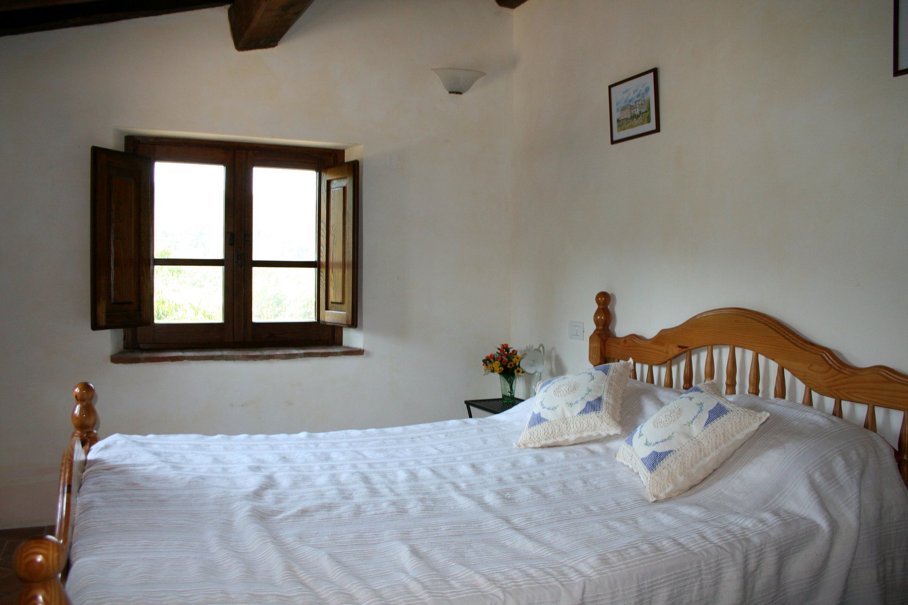 A bright double bedroom with shuttered windows and timber beams