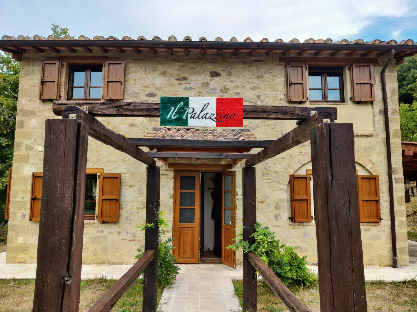 The stone façade of Il Palazzino with wooden shutters and the garden entrance