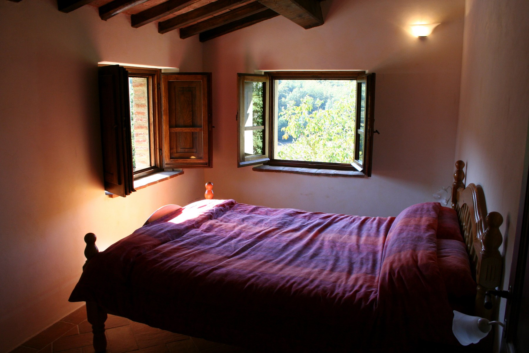 A double bedroom with timber beams and shuttered garden windows