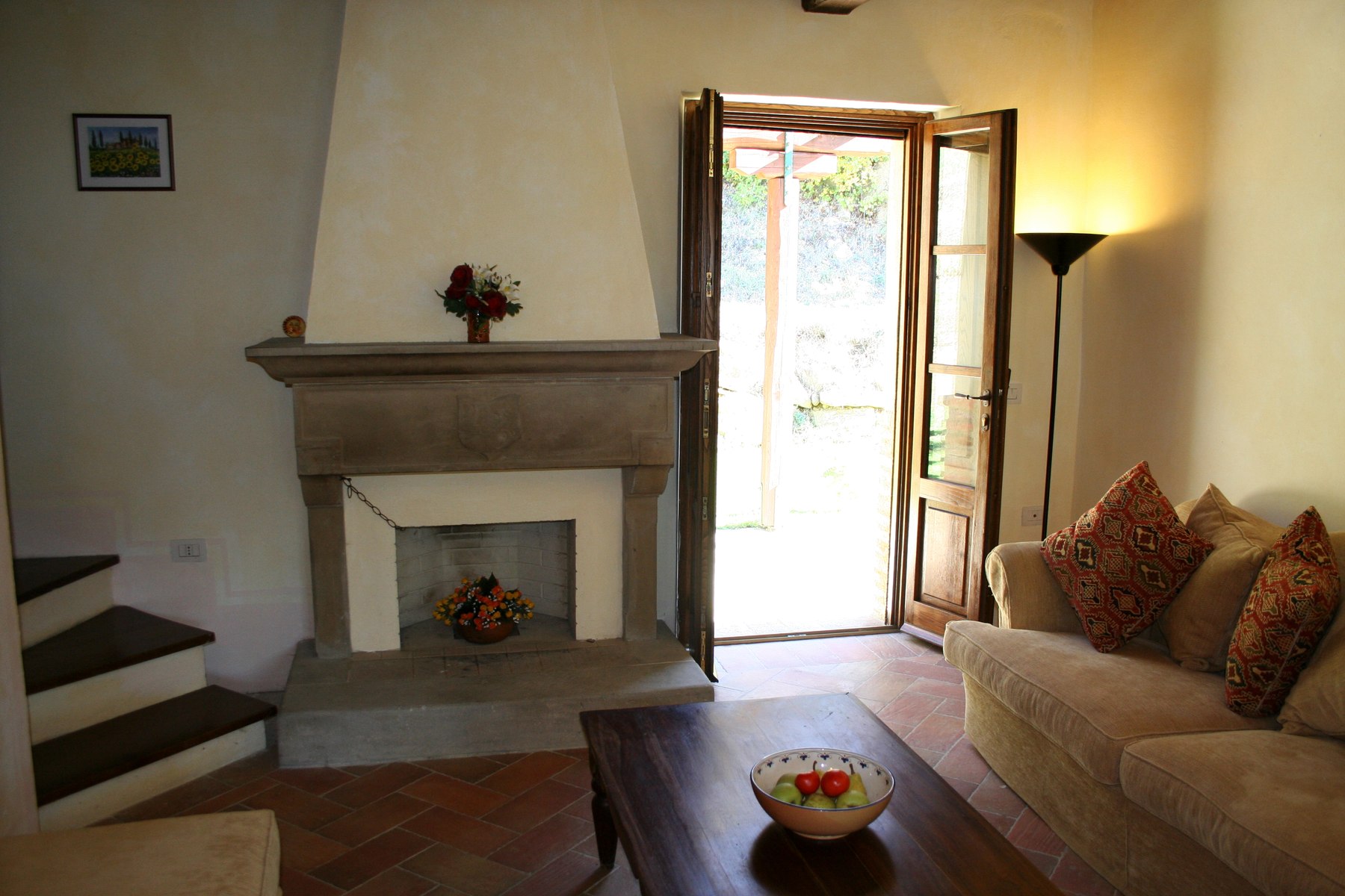 The sitting room with a pietra serena fireplace and a door leading towards the pergola